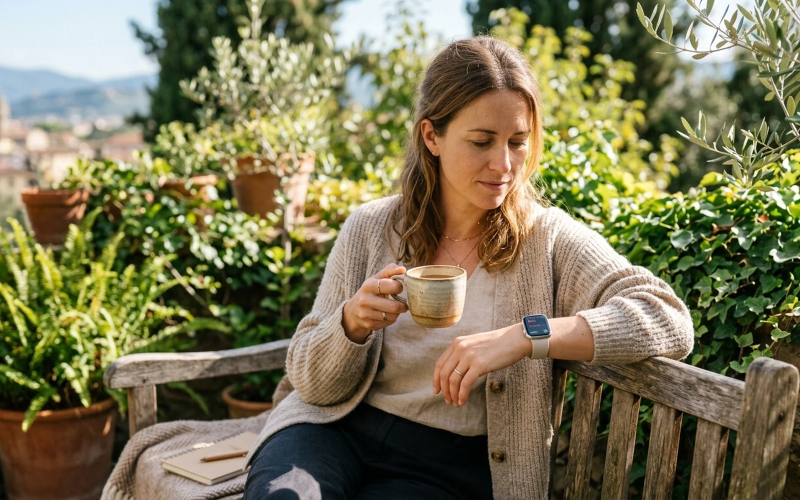A person pausing on a sunny terrace to check health metrics on a smartwatch